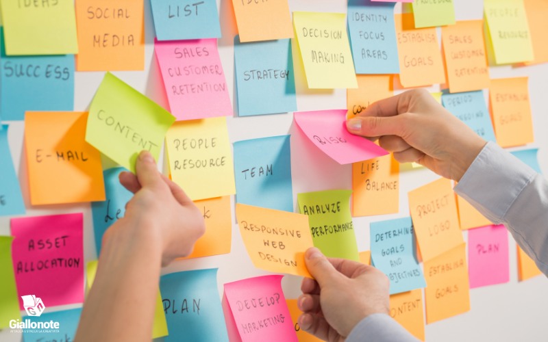 Post-it colorati attaccatti alla lavagna con pensieri, obiettivi e cose da fare per organizzare il lavoro